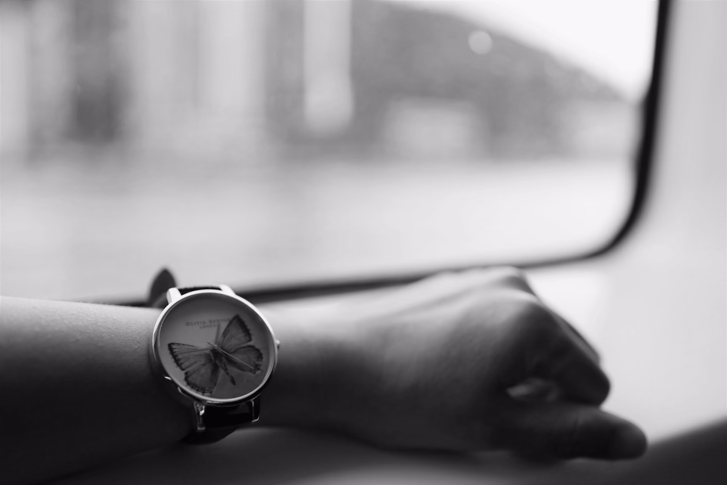 A watch on a wrist by an aircraft window