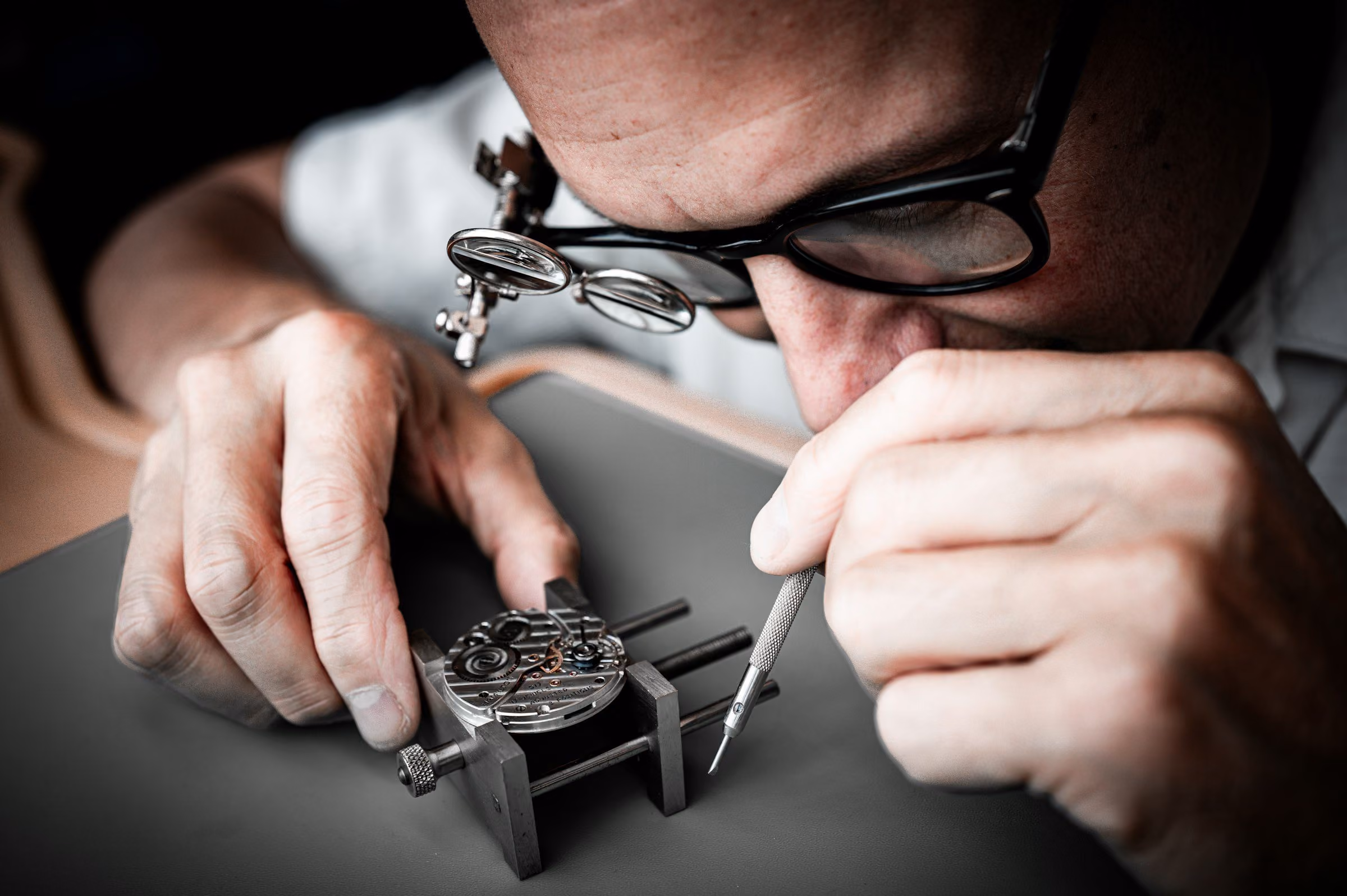 Buying pre owned watches: a watchmaker with a loupe checking a movement