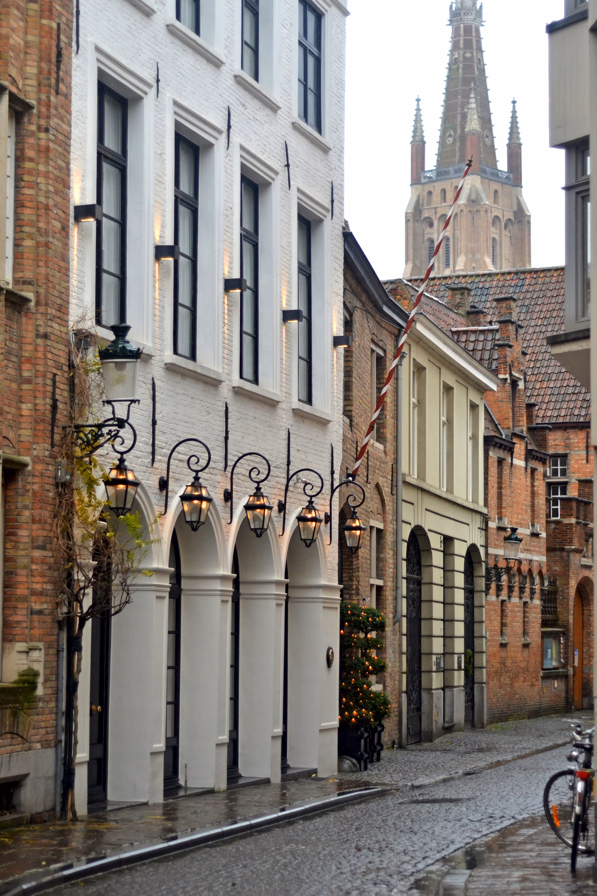 A quiet Bruges lane below a church tower