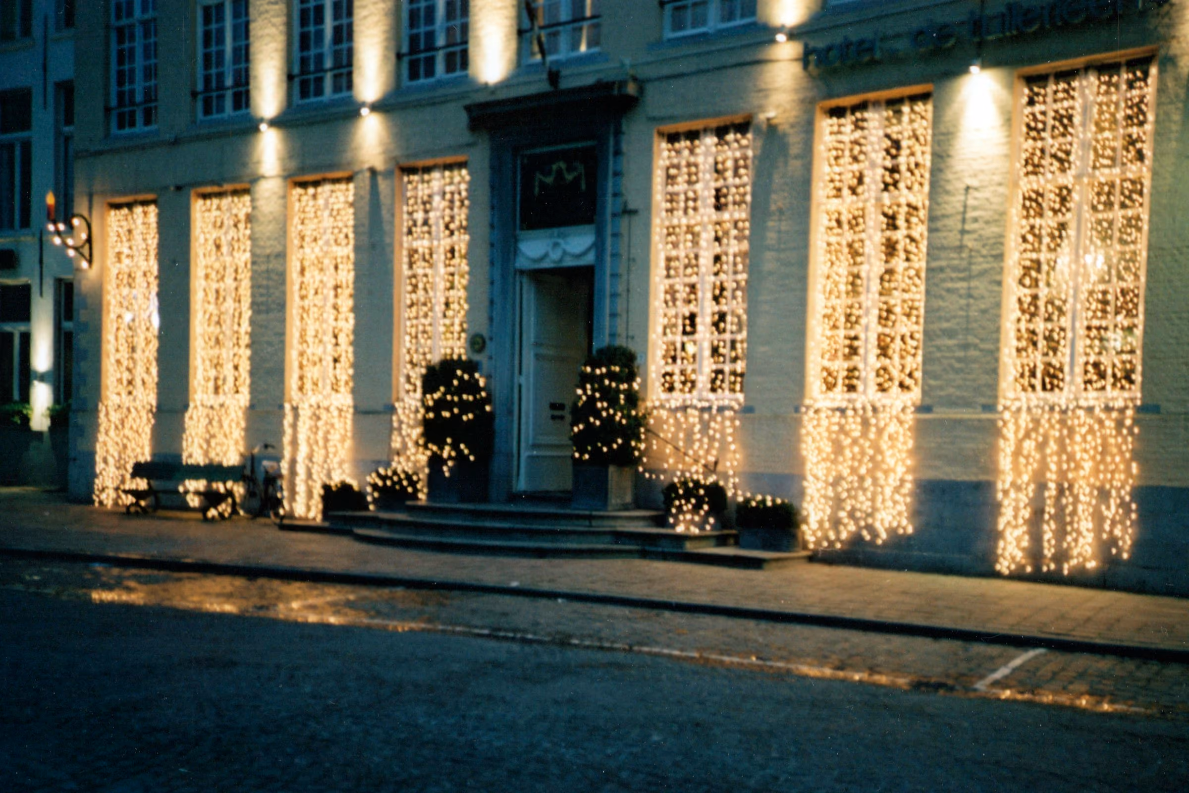 A Bruges building curtained in white lights