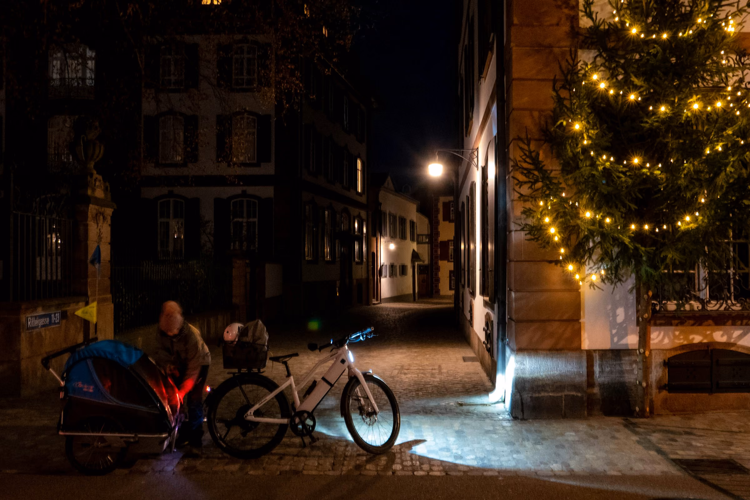 A lit tree on an old town street at night