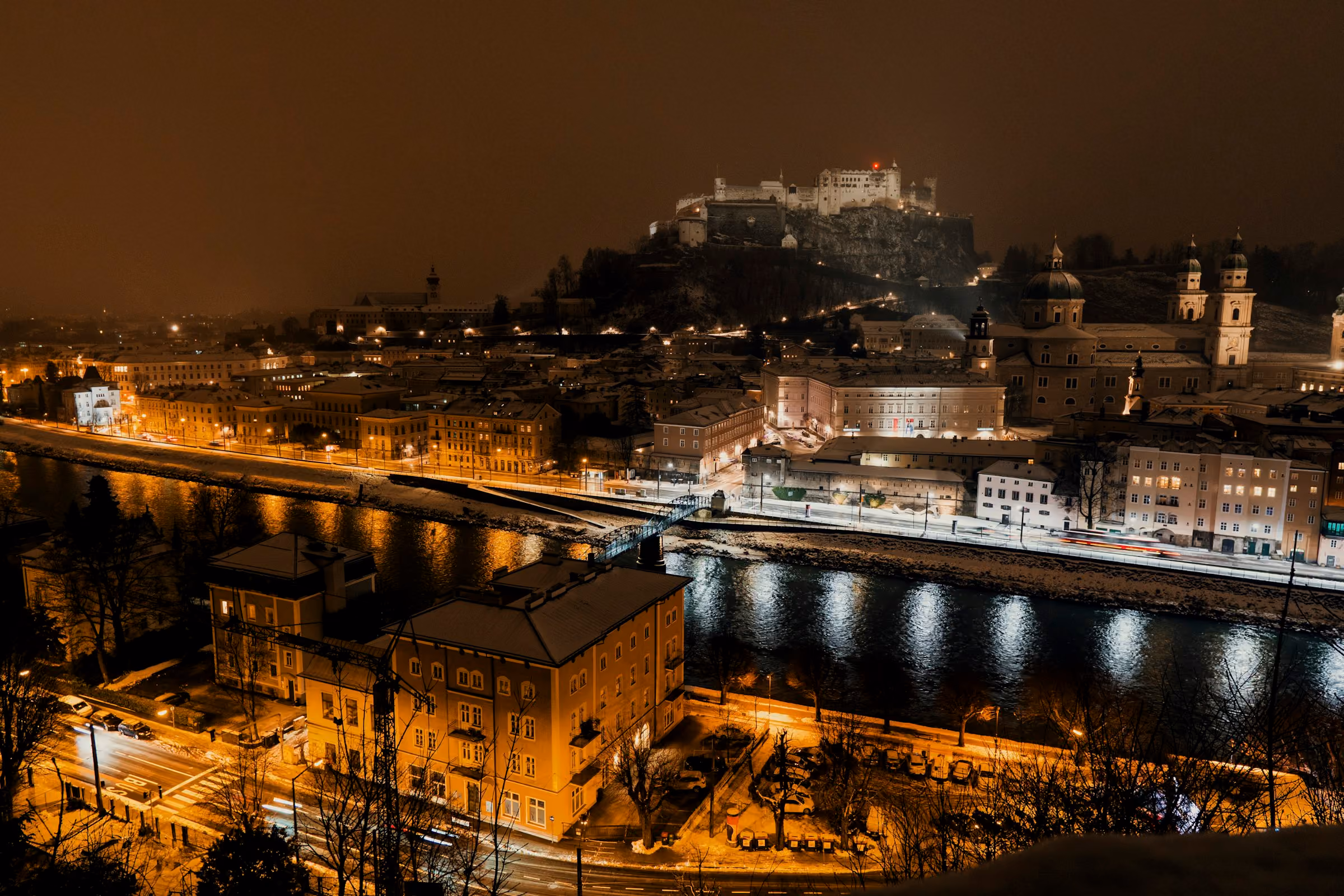 Salzburg and the river at night with the fortress lit above